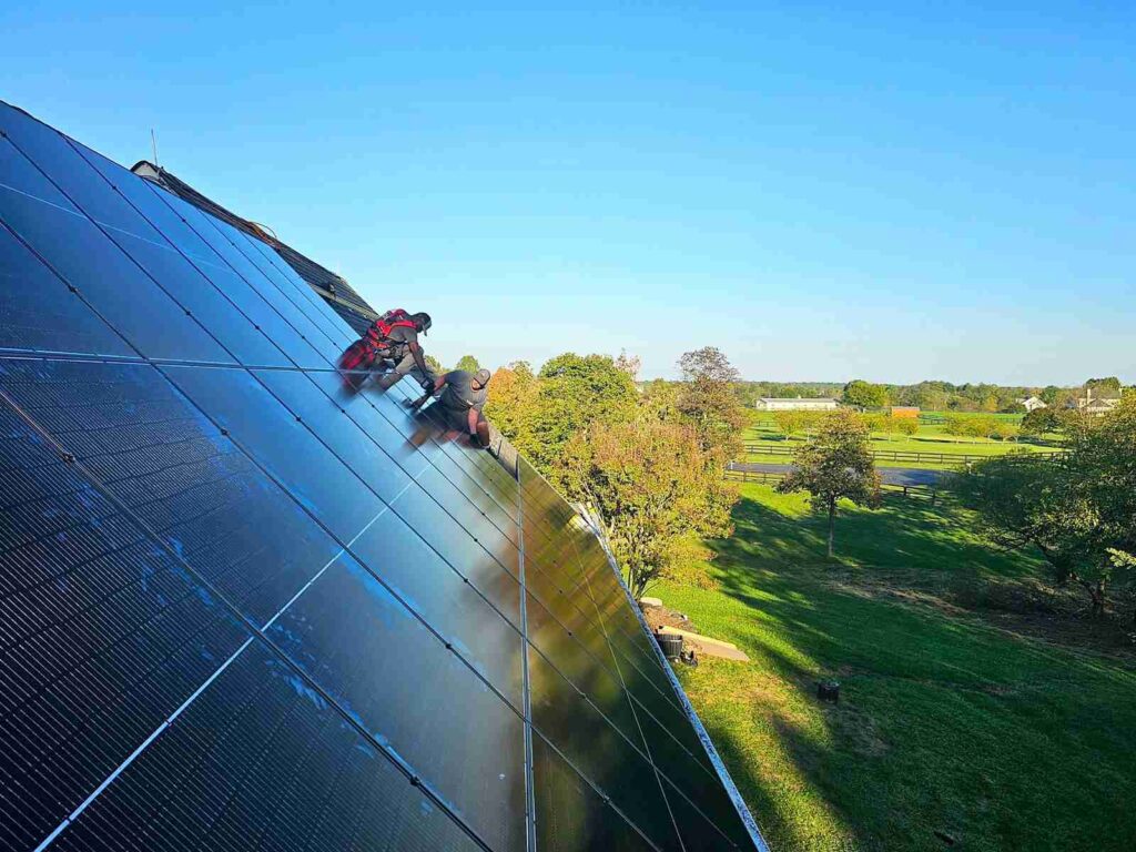 Two solar installers on a rooftop in Virginia bolting solar panels into place.