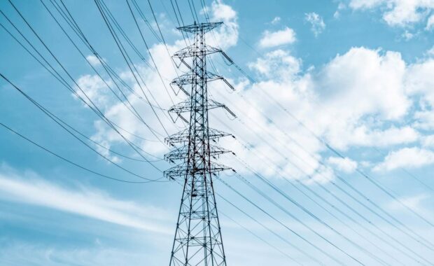 Power lines against a blue sky with white fluffy clouds.