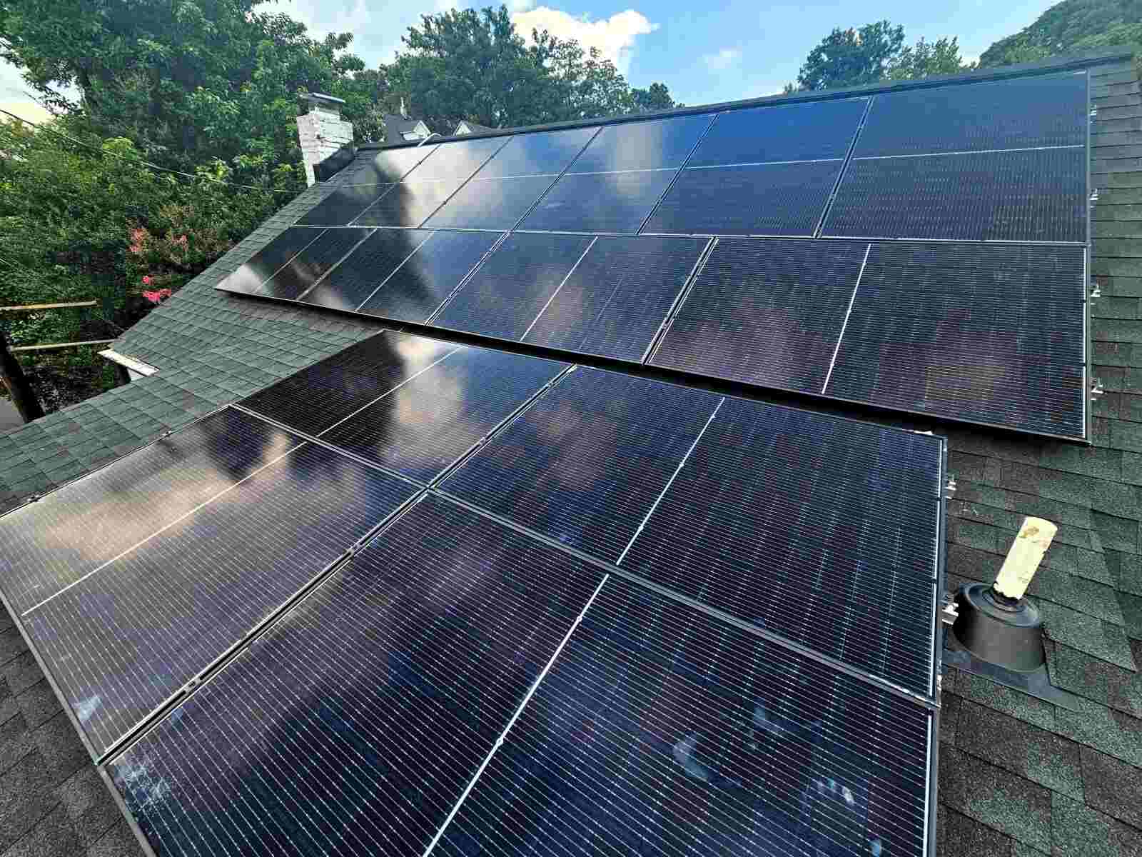 Blue solar panels reflecting the sky on a rooftop.