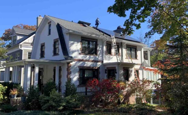 A home in Washington, DC with two solar installers on the roof, installing solar panels.