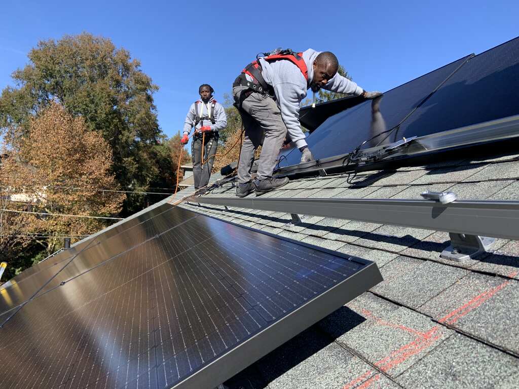 Two solar installers complete a residential rooftop solar installation.