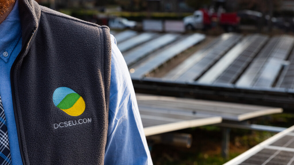 A representative of the DC Sustainable Energy Utility stands in front of solar panels.
