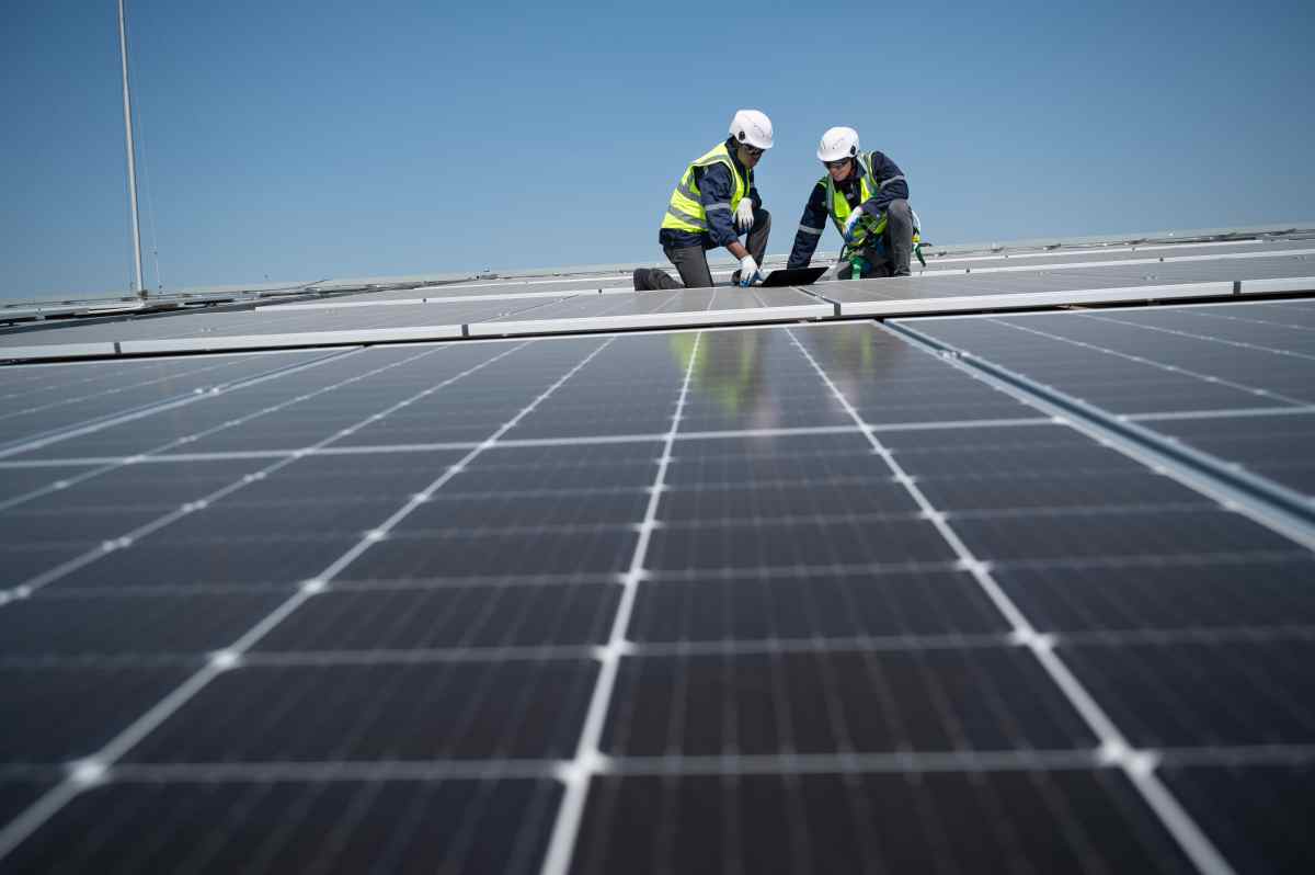 two solar panel experts on roof of building inspecting solar panels