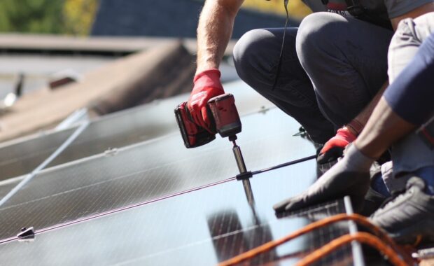 A close-up view of two installers bolting in a solar panel.