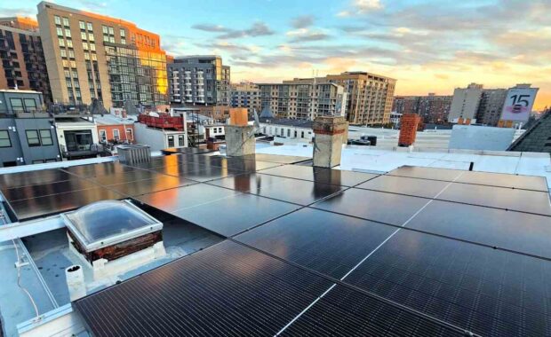 Solar panels on a flat roof with a city background.