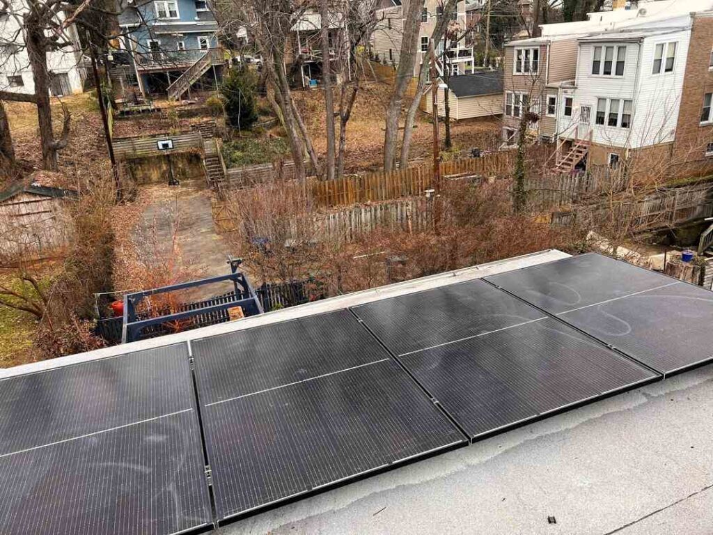 Solar panels on a flat roof extension with a winter city landscape in the background.