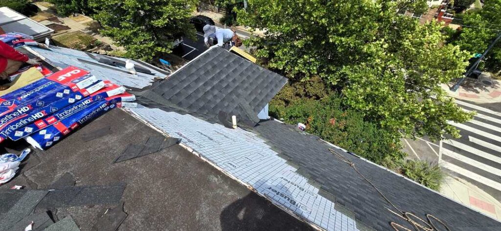 A roofer works on a pitched shingle roof.