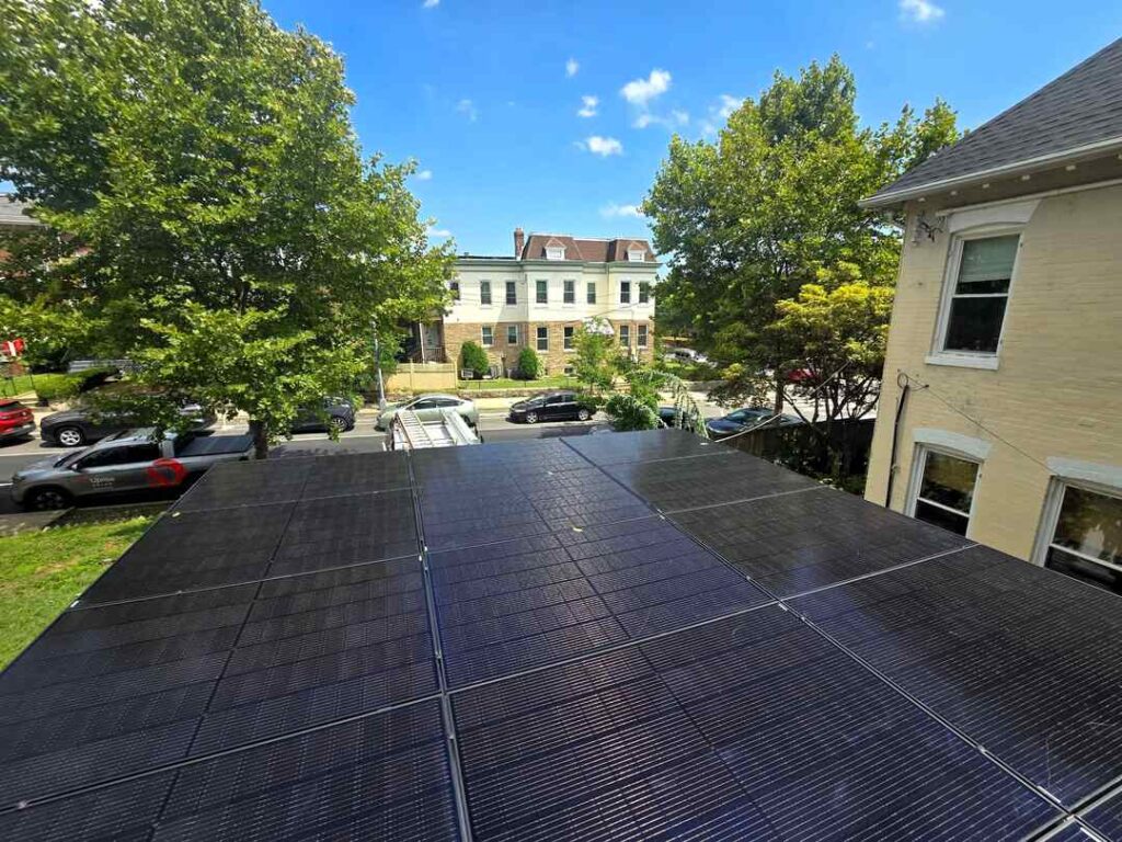 Solar panels on a roof with a home in Northwest DC in the background.