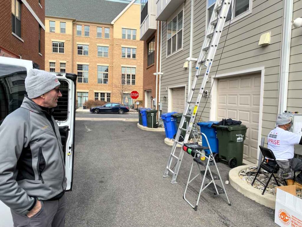 Customer William Tinel looks on as an Uprise solar installer works on wiring.