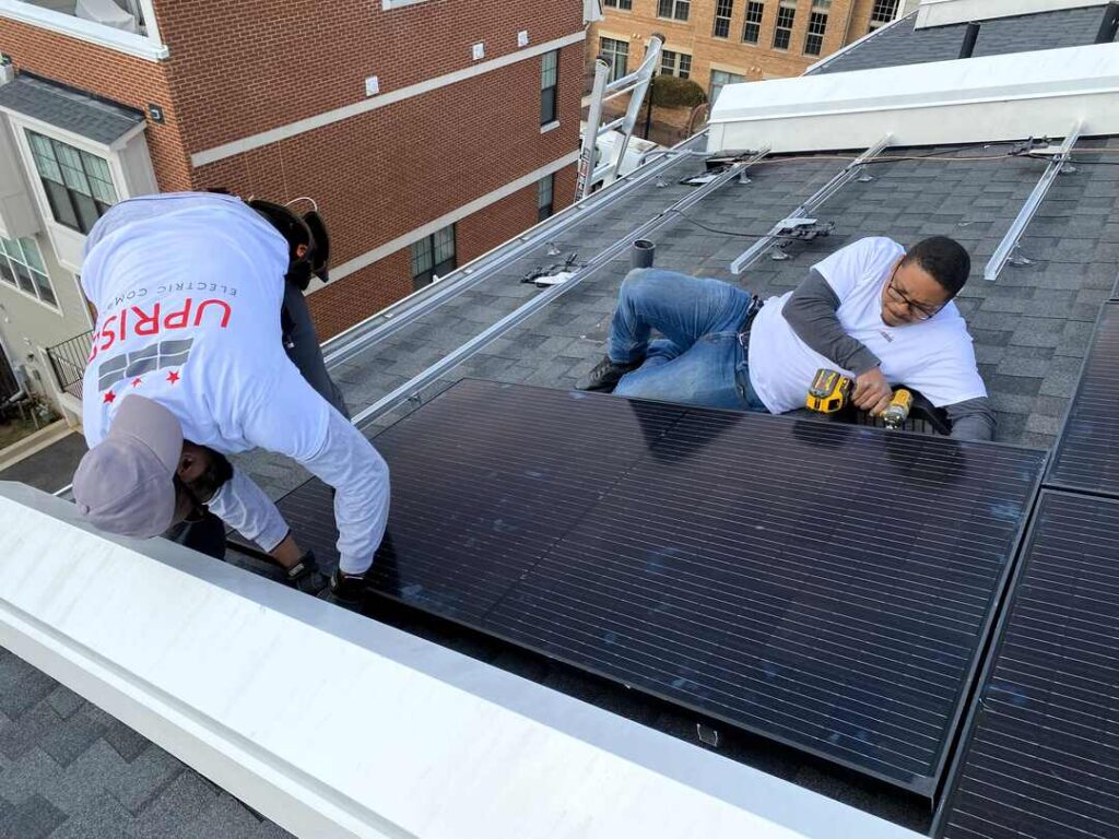 Two Uprise installers attach a solar panel to the racking system.