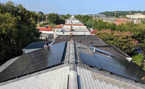 Solar panels on a pitched roof with flat roofs in the background.