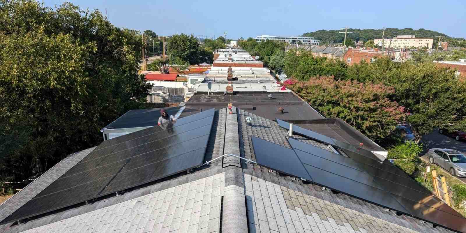 Solar panels on a pitched roof with flat roofs in the background.