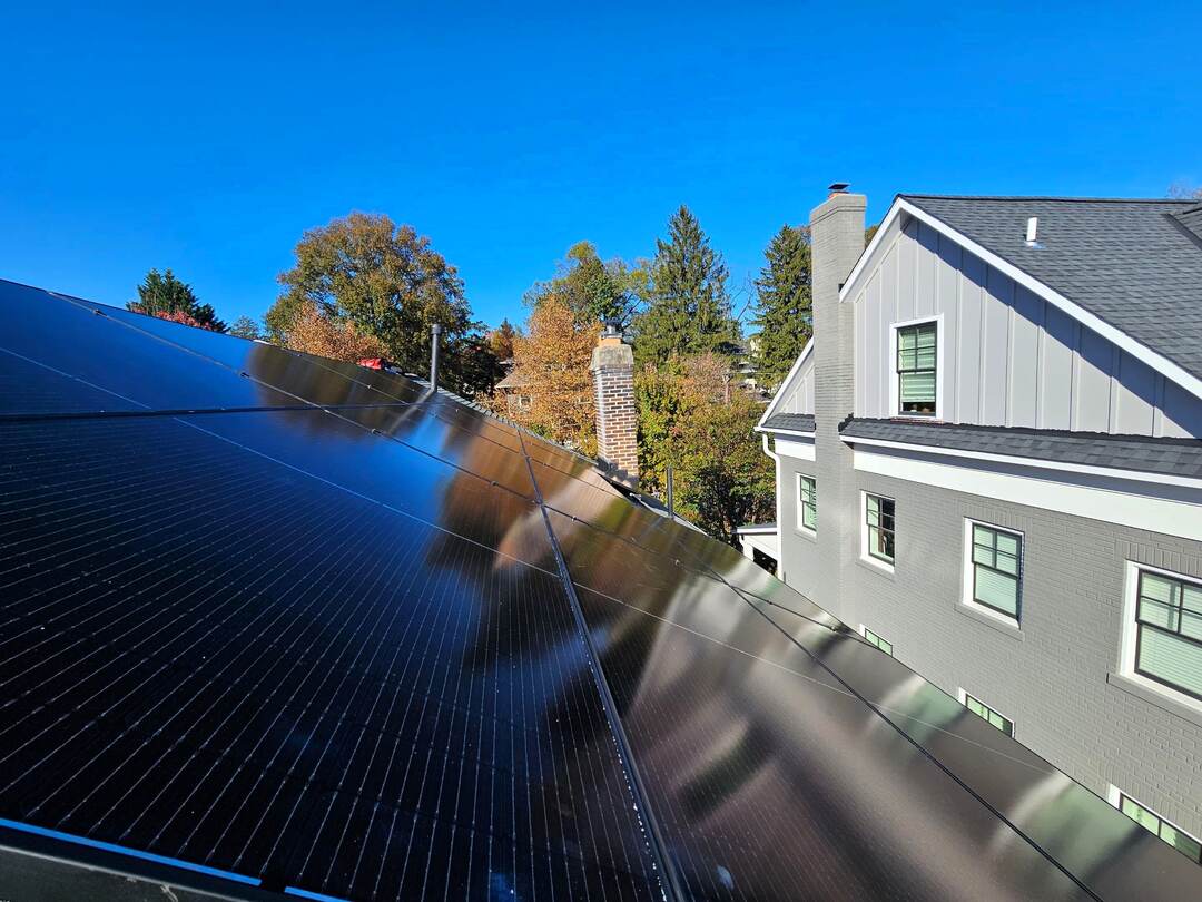 Close-up of solar panels on a pitched roof under a blue sky.