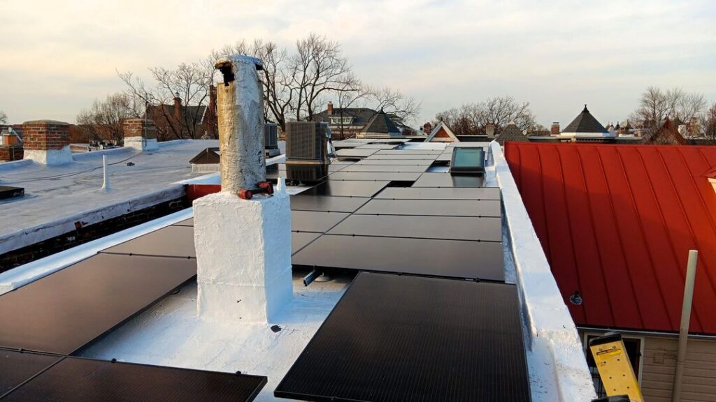 Solar panels on a flat roof in Northeast Washington, DC next to a curved red roof.