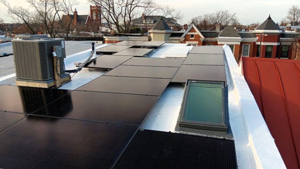 Solar panels and a skylight on a white flat roof.