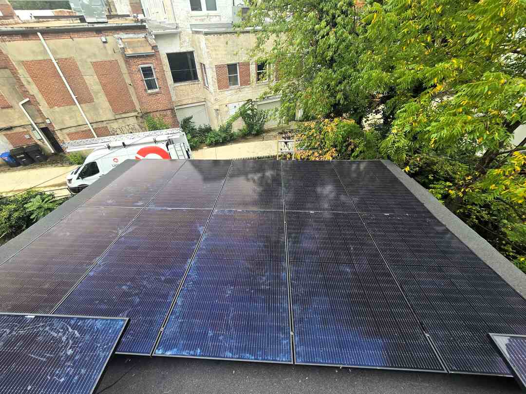 Solar panels on a flat roof with an Uprise Solar truck in the background.