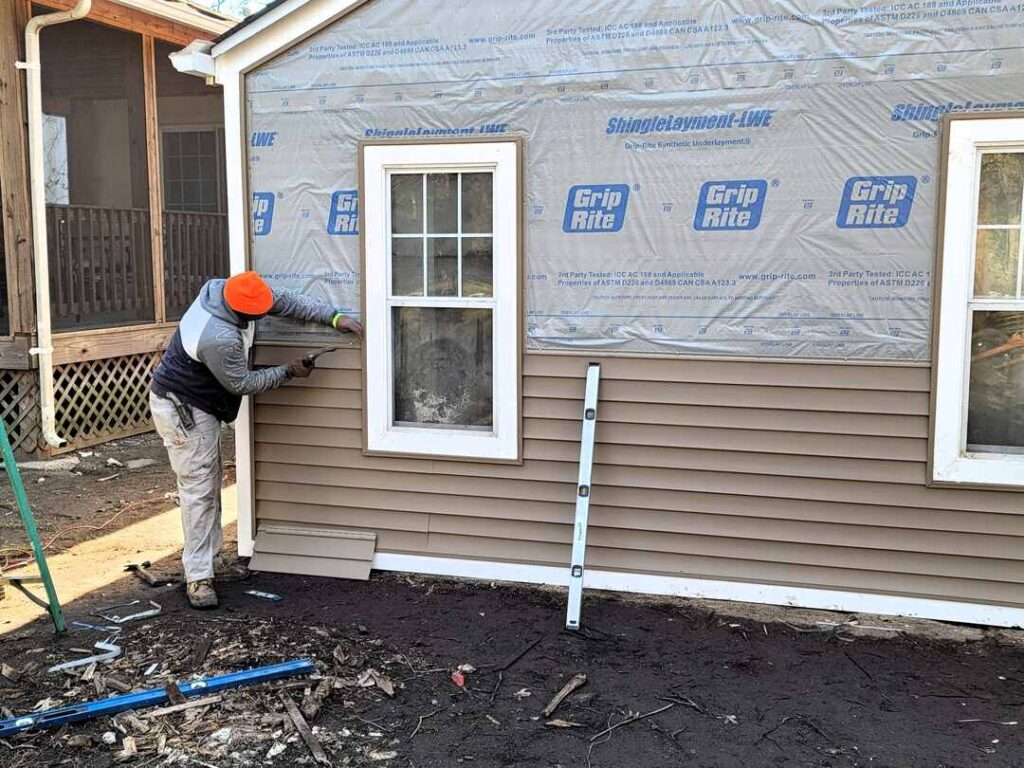 A worker doing the siding on a Maryland garage for this roofing project.