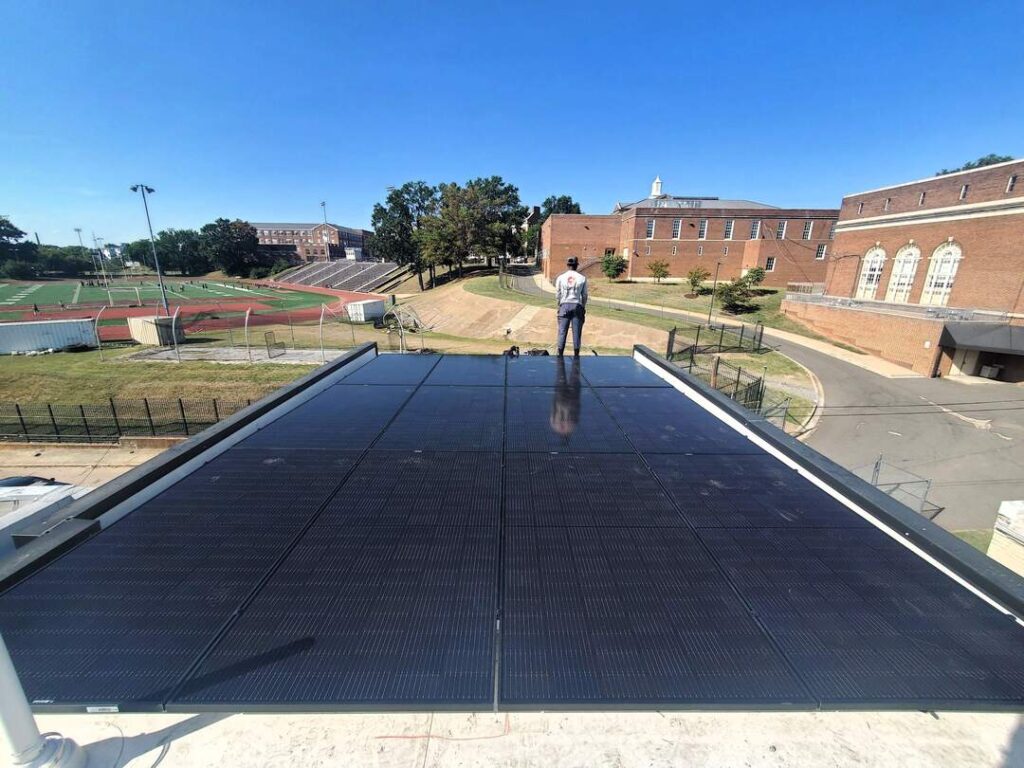 An Uprise Solar worker stands beside a completed solar array in Northeast DC.