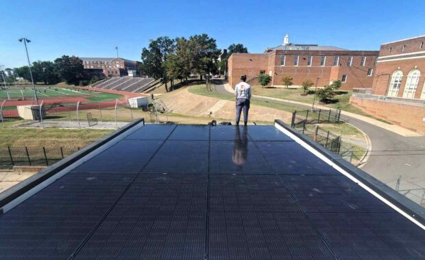 An Uprise Solar installer stands near a completed solar array.