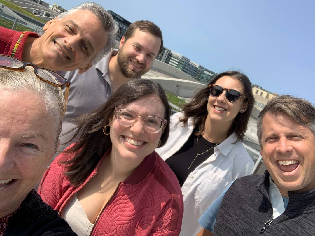 Six Uprise Solar team members smiling on a roof on a sunny DC day.