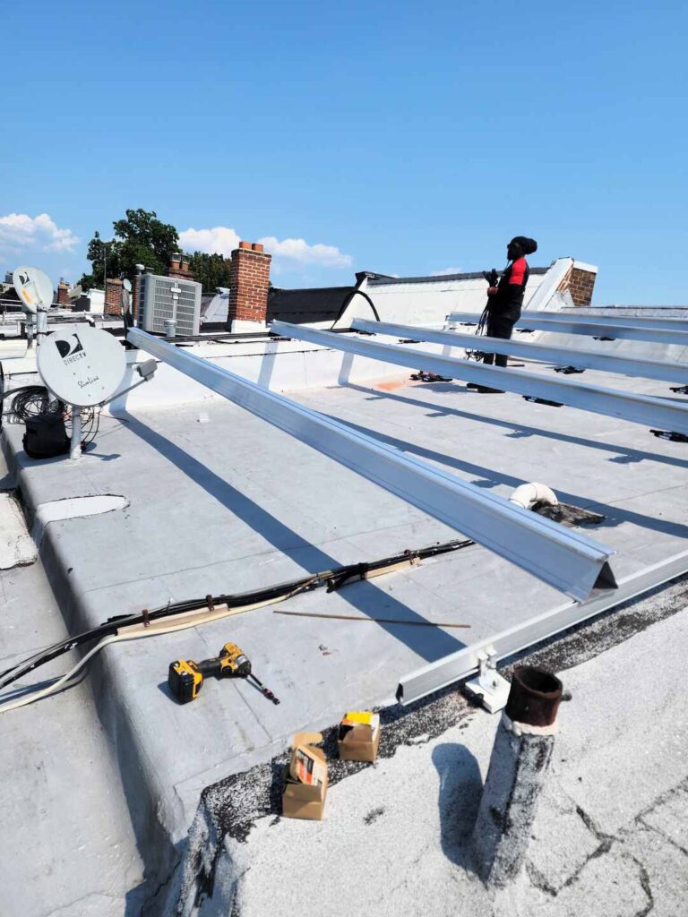 An Uprise Solar installer stands near racking installed on a flat roof.