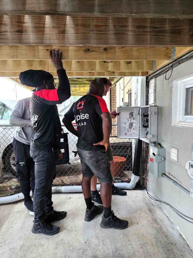 Solar installers work on wiring for an installation.