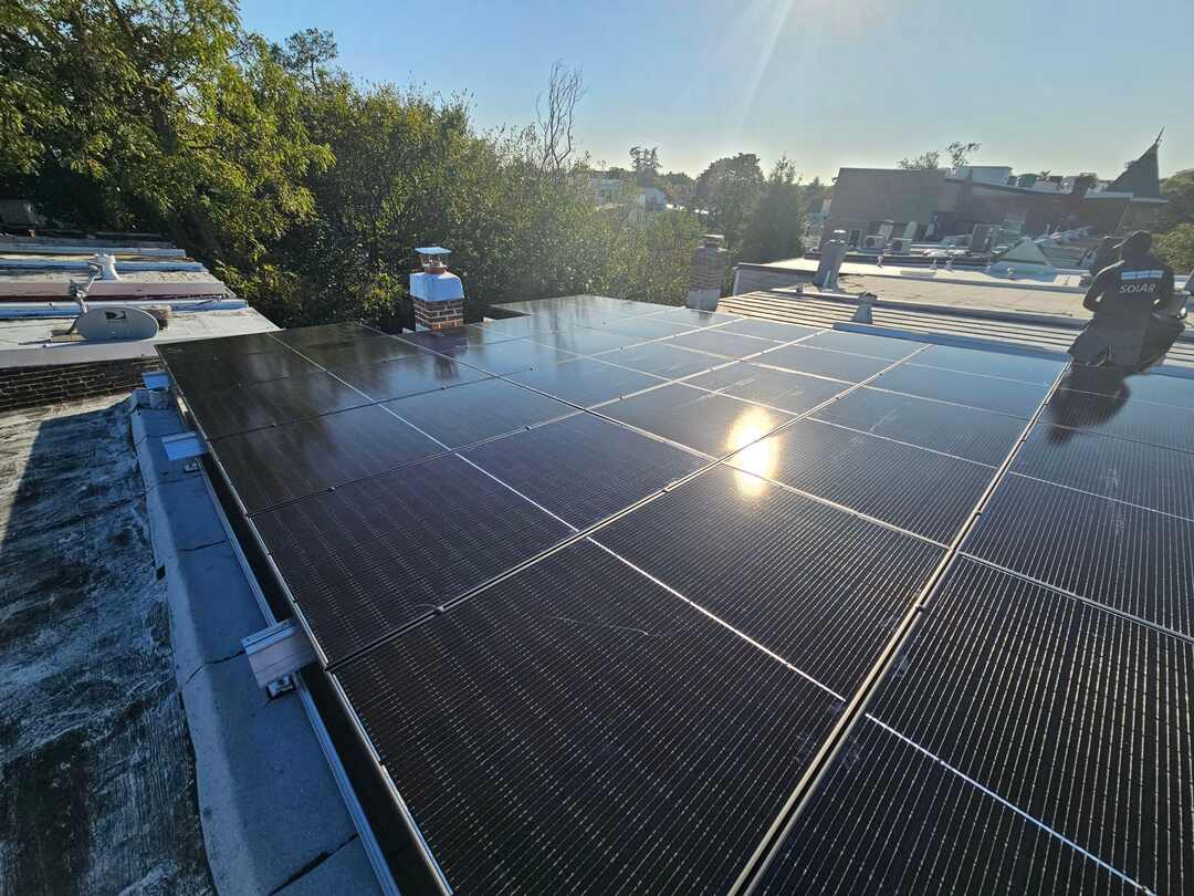 Sunlight on a solar array with a solar installer nearby.