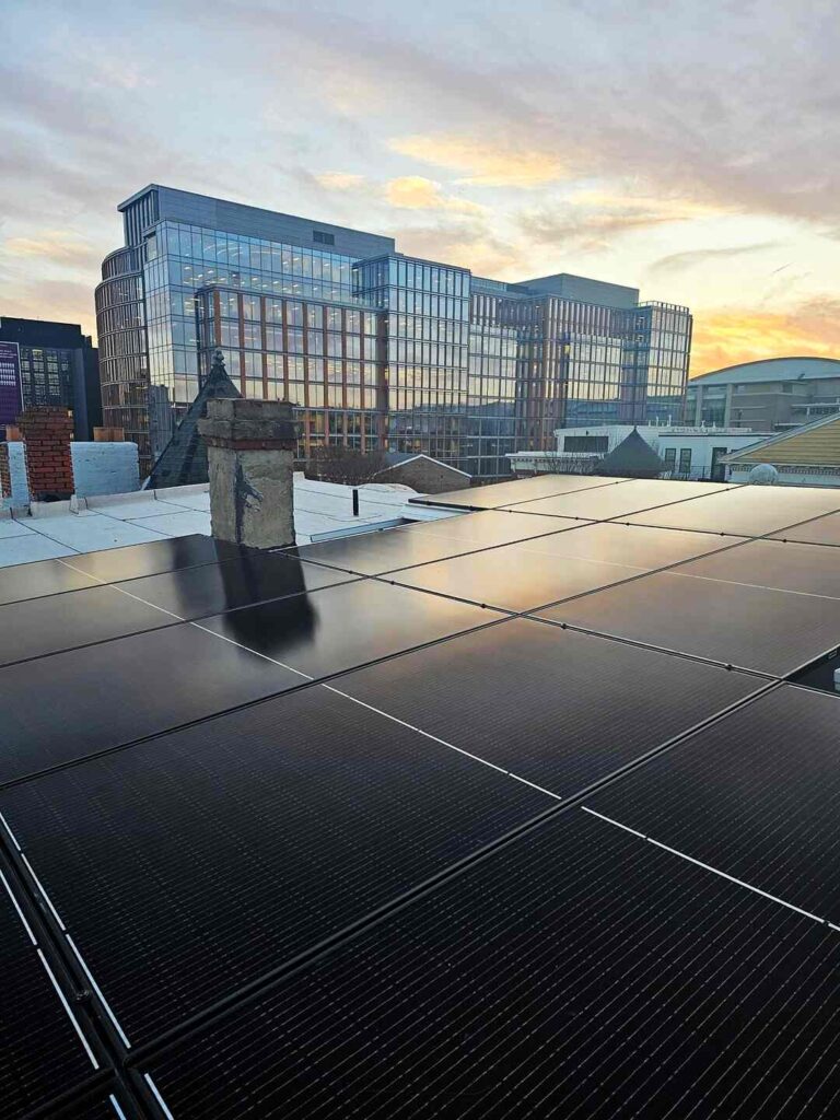 Rooftop solar with city buildings in the background under a sunset.