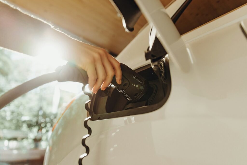 A person plugging a charger into an electric vehicle.