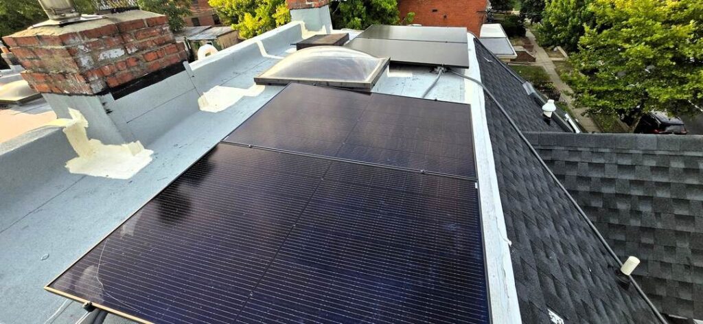 Solar panels near a skylight on a roof.