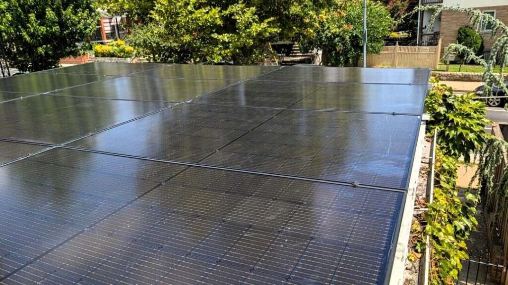 Solar panels on a flat roof surrounded by greenery.