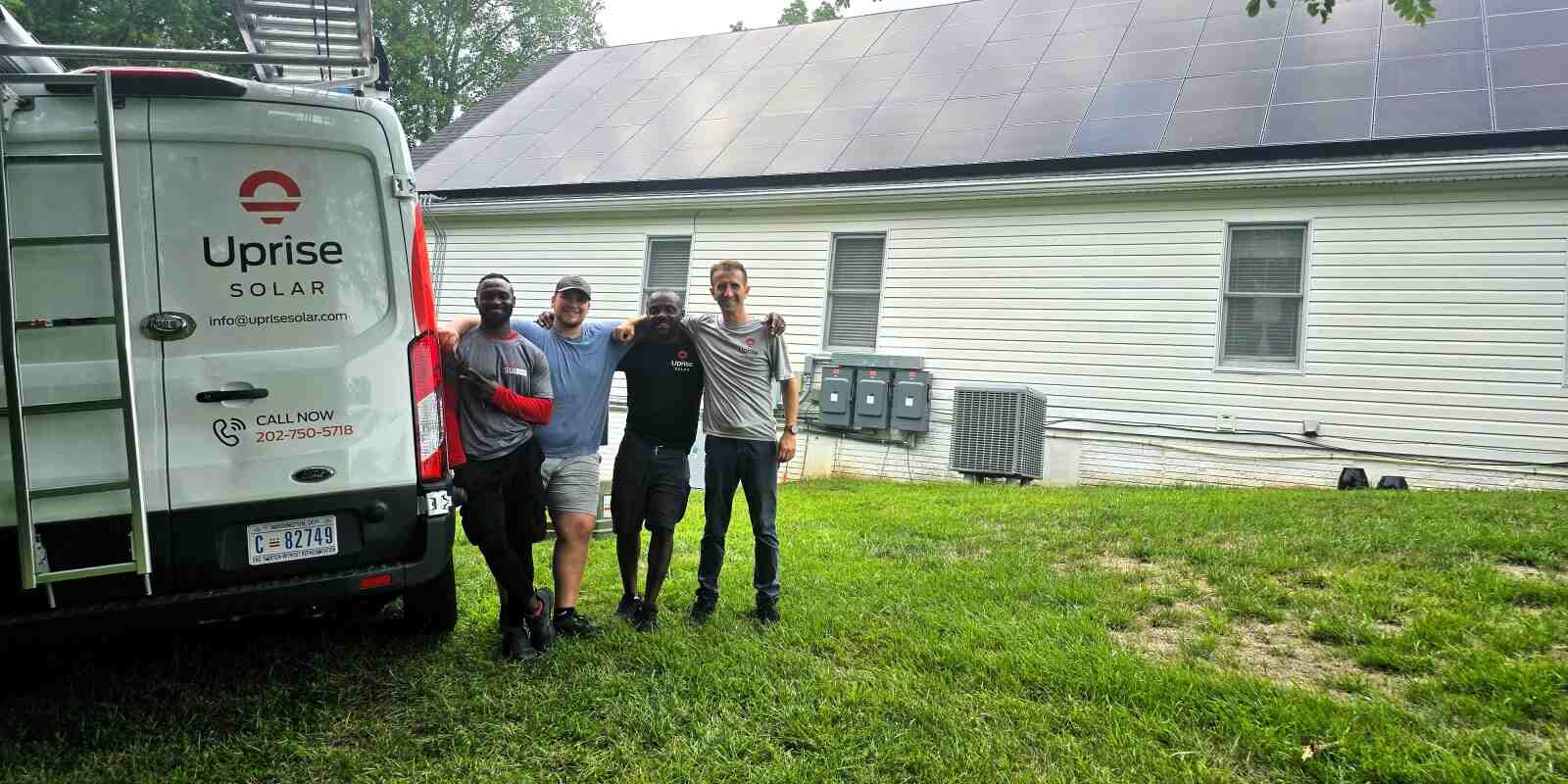 Four Uprise Solar installers stand next to the truck, in front of a finished solar array in Virginia.