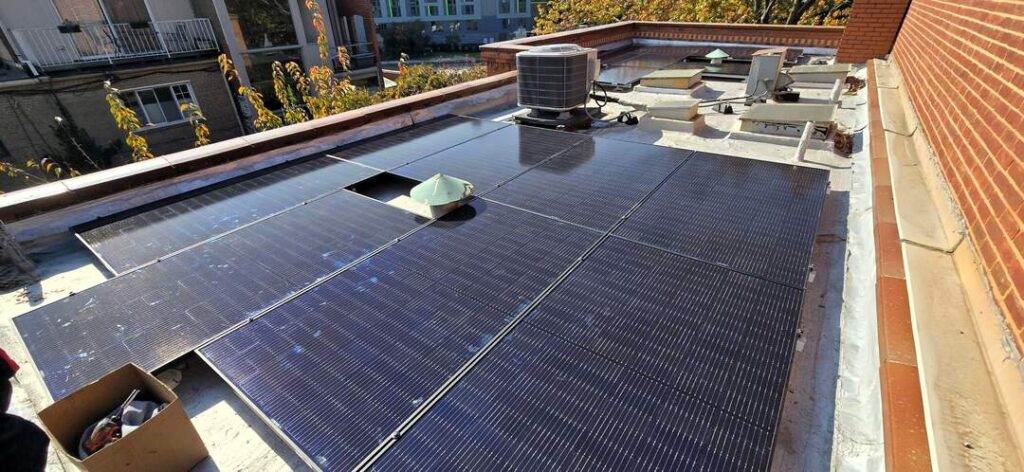 Solar panels on a flat roof surrounded by brick parapets.