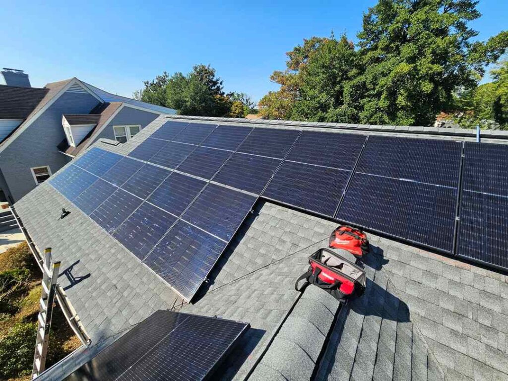 Two red tool bags rest near a solar array on a pitched roof in Southeast Washington, DC.