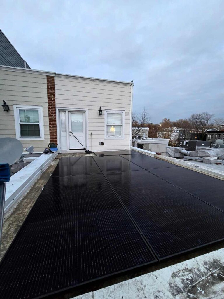 The doorway of a home opening onto a solar array on a flat roof.