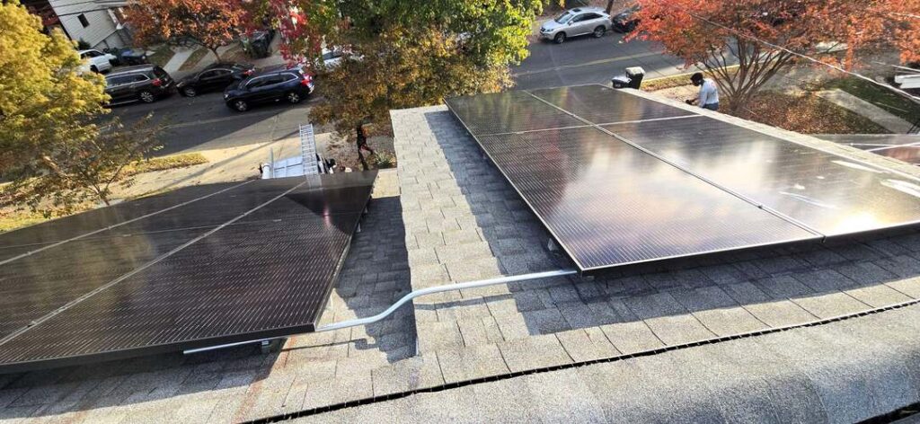 Solar panels on a gray pitched roof with conduit running between.